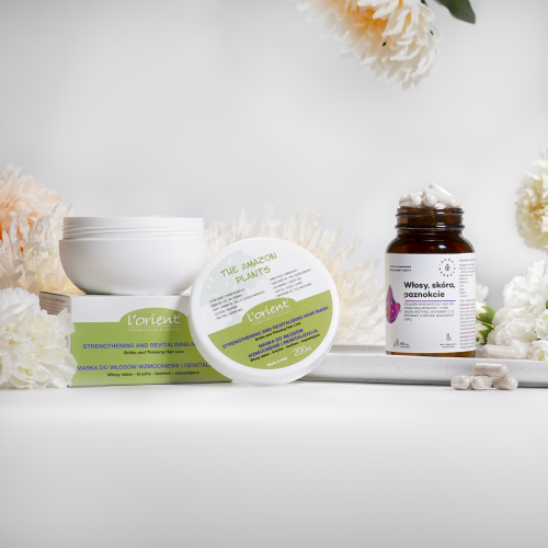 Eksponowane są dwa produkty kosmetyczne aura herbals - zestaw 5-3: biały słoik z napisem Maseczka wzmacniająca i rewitalizująca oraz brązowa butelka z kapsułką, otoczona białymi i brzoskwiniowymi kwiatami.