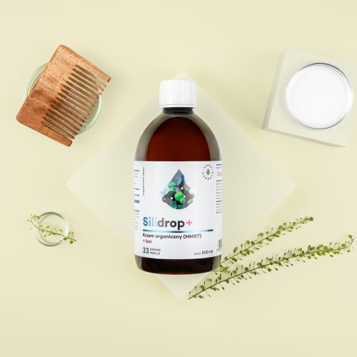 Butelka z etykietą Silidrop-krzem-organiczny-MMST-bor-plyn-500-ml_1500x1500-2 znajduje się na beżowym tle, w pobliżu drewnianego grzebienia, słoika z białą pokrywką, okrągłego szklanego pojemnika i zieleni.