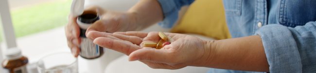 Kobieta łyka witaminę C i witaminę D w formie kapsułek