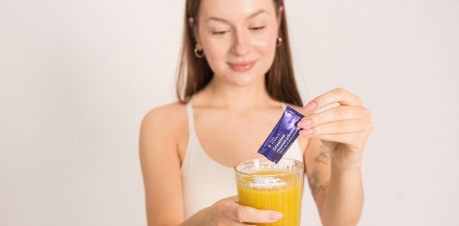 Kobieta wsypuje monohydrat kreatyny z glicyną do szklanki z wodą