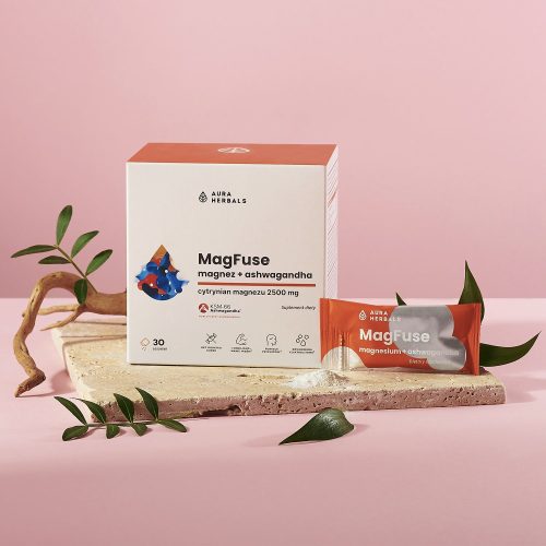 Pudełko i saszetka suplementu MagFuse z magnezem i ashwagandhą (30 szt.) firmy Aura Herbals, przedstawione na kamiennej płycie z liśćmi i na różowym tle.