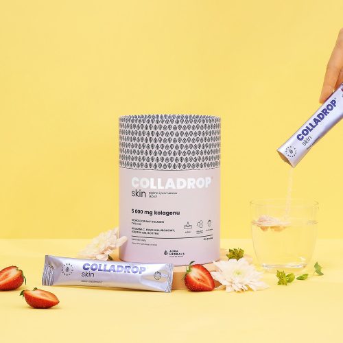 Ręka wsypuje proszek kolagenowy Colladrop Skin Truskawka Saszetki (colladrop-skin-truskawka-saszetki-5_1500x1500) z saszetki do szklanki wody, a na żółtym tle widoczne są truskawki i kwiaty.