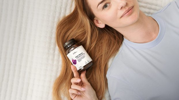 Kobieta trzyma w dłoniach najlepszy suplement na włosy Hair Mania AUra Herbals z keratyną