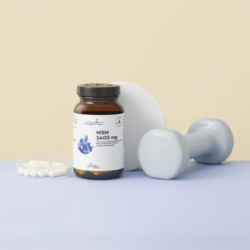 Butelka z etykietą „MSM-1400-mg-siarka-organiczna-kapsułki-60-szt_2_1500x1500” jest przedstawiona obok białych tabletek na talerzyku, jasnoniebieskiego hantla oraz okrągłego białego przedmiotu na jasnoniebieskiej powierzchni.