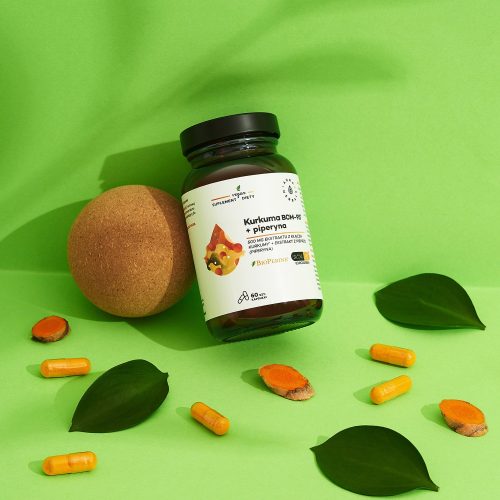 Butelka produktu „kurkuma-500-mg-bcm-95-piperyna-kapsułki-60-szt_2_1500x1500” jest otoczona kapsułkami, plasterkami kurkumy, zielonymi liśćmi oraz brązową kulą na zielonym tle.