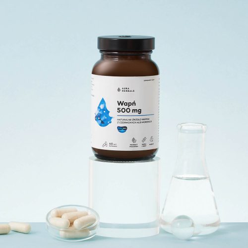 Na jasnoniebieskim tle stoi brązowa butelka z etykietą o kodzie c88f21de-2d84-47fe-8e37-ab40553856f2, umieszczona na przezroczystym walcu, a obok niej znajduje się szklana kolba i kilka białych kapsułek.