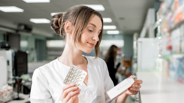Magister farmacji w aptece czyta etykietę witamin na odporność